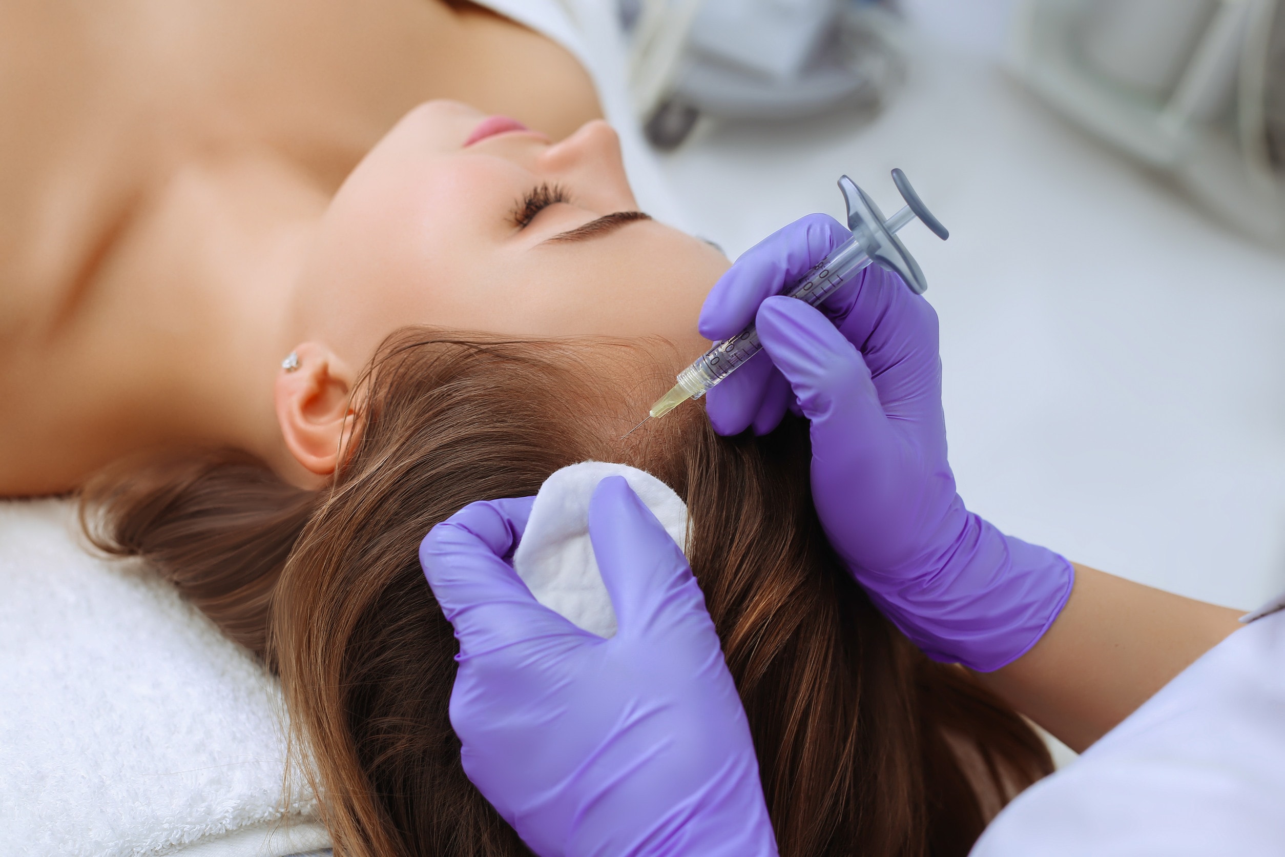 Un chirurgo che esegue un trapianto di capelli su una donna.